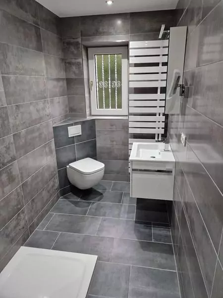 Grau gefliestes Badezimmer mit Toilette und Waschtisch