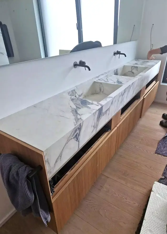 Modernes Badezimmer mit zwei Waschbecken aus weißem Marmor und Holzschränken darunter