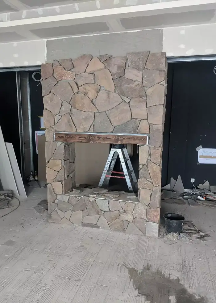 Kamin im Wohnzimmer mit Natursteinen wird fertig gestellt