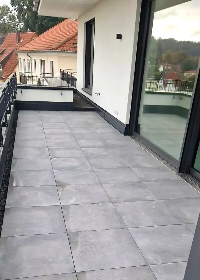 Moderner großer Balkon wurde mit grauen Steinfliesen ausgelegt